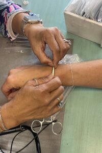 A jeweler adjusts a chain on a client’s wrist in preparation for welding, highlighting the Permanent Jewelry in Panama City Beach experience