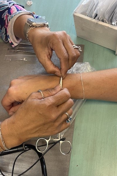 A jeweler adjusts a chain on a client’s wrist in preparation for welding, highlighting the Permanent Jewelry in Panama City Beach experience